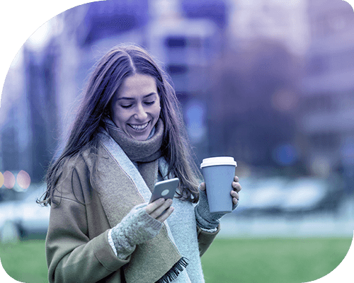 Frau mit Kaffeebecher schaut auf ihr Smartphone